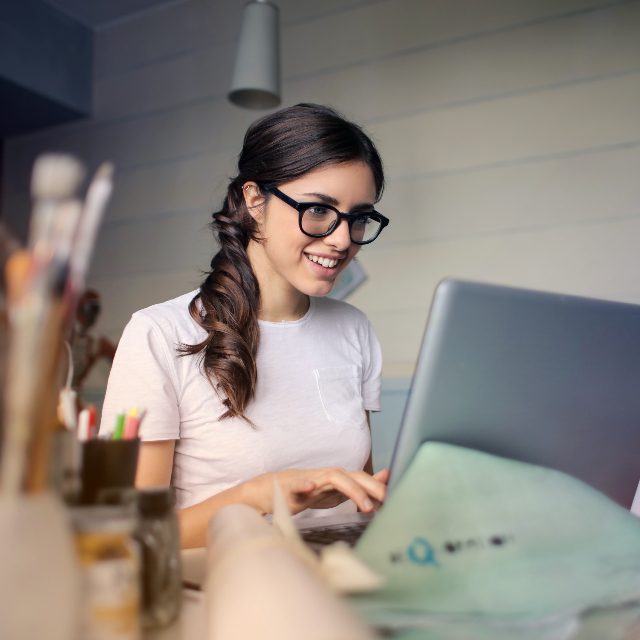 Estudiante sonriendo mientras aprende desde su computadora